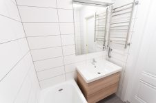 Белая ванная комната, зеркало, раковина, электрический полотенцесушитель