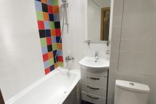 Угол над ванной оформлен разноцветной плиткой